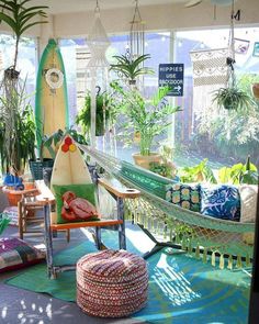 a living room filled with lots of furniture and plants on the windowsill, along with a hammock hanging from the ceiling