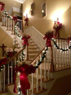 christmas decorations on the banisters and stairs are decorated with red bows, lights and garland