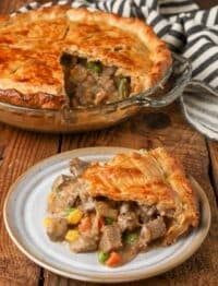 there is a pie with meat and vegetables in it on the plate next to another pie