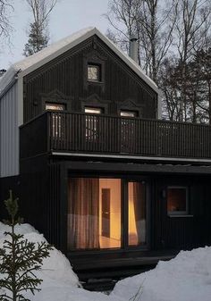 a black house is surrounded by snow and trees