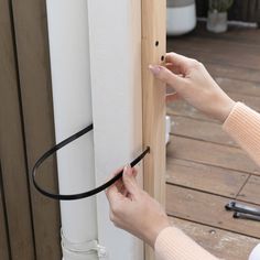 a woman is opening the door with a black handle on her left hand and another hand holding an object in it's other hand