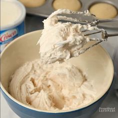 a bowl filled with whipped cream next to muffin tins