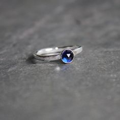 Do you need a gift for someone with a September birthday or to celebrate your 5th wedding anniversary? This sterling silver synthetic sapphire stacking ring is perfect if your birthstone is sapphire or you need a simple navy blue ring. Here are the details:This ring is made with either a rose cut (faceted) or smooth 5mm synthetic sapphire cabochon set in a sterling silver bezel and on a sturdy band handmade in your size. It can be worn with other stackable rings, or by itself.Please select your Minimalist Blue Sapphire Ring For Anniversary, Blue Sapphire Stackable Birthstone Ring, Modern Topaz Birthstone Ring As Gift, Stackable Blue Birthstone Promise Ring, Modern Sapphire Birthstone Ring For Promise, Modern Topaz Ring As Birthstone Gift, Modern Sterling Silver Sapphire Ring As A Gift, Modern Sterling Silver Sapphire Ring Gift, Modern Sapphire Ring Birthstone