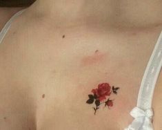 a woman's chest with a rose tattoo on the left side of her breast