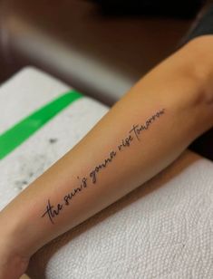 a woman with a tattoo on her arm that says the story is never told in cursive writing