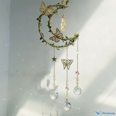 a wind chime with butterflies and crystals hanging from it's sides, on a white wall