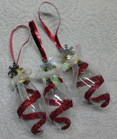 three christmas ornaments hanging from red and white ribbons