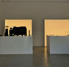 an empty room with two large white tables in front of the wall and lights behind them