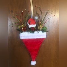 a red and white christmas stocking hanging on a door with greenery in it