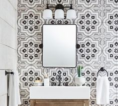 a white sink sitting under a bathroom mirror next to a wooden cabinet and towel rack