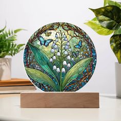 a glass plate with flowers and butterflies on it sitting on a table next to a potted plant