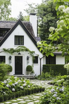 a white house is surrounded by greenery and bushes in front of the door area