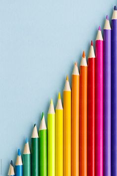 many colored pencils lined up in a row on a blue background by paul phillips for stocks & bond