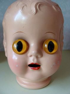 a close up of a doll head with yellow eyes