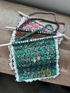 several different types of beaded jewelry on a piece of wood with two knitting needles