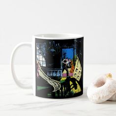 a coffee mug sitting on top of a table next to a doughnut and donut