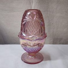 a pink glass vase sitting on top of a table