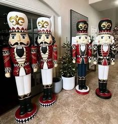 four wooden nutcrackers are lined up in front of a door and christmas tree