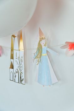 a paper doll is hanging on a clothes line next to other items that have been cut out