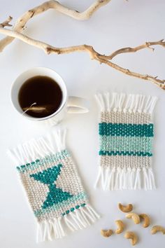 two white and green knitted mitts next to a cup of coffee on a branch