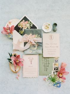 the wedding stationery is laid out on top of the table with flowers and other items