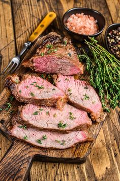 sliced steak with herbs and seasoning on cutting board next to other foodstuffs