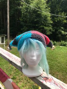 a white mannequin head with multicolored knitted hats on it's head