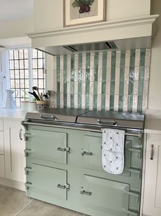 an old fashioned stove in a kitchen with green and white tiles on the backsplash