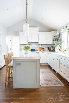 a large kitchen with white cabinets and wooden flooring, an island in the middle