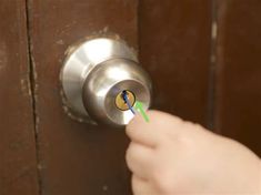 a person is opening a door with a key in their left hand and there is a green light coming from the lock