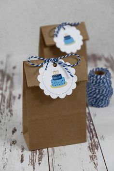 two brown paper bags with blue and white tags on them sitting next to some twine spools