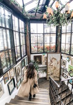 a woman is walking down some stairs in a room with many pictures on the walls