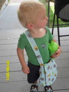 a little boy holding a green toy in his hand and wearing a tie around his neck