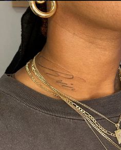 a close up of a person's neck with gold chains and tattoos on it