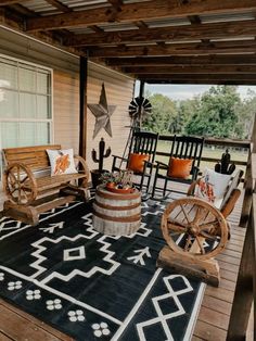 an outdoor porch with rocking chairs and rugs on the wooden flooring, along with two wagon wheels