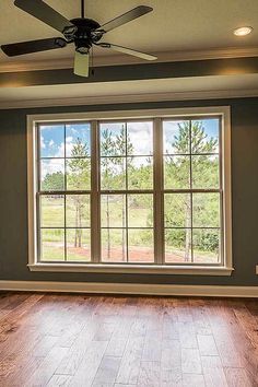 an empty room with wood floors and a ceiling fan in the middle of the room