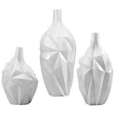 three white vases sitting next to each other on a white surface with geometric shapes