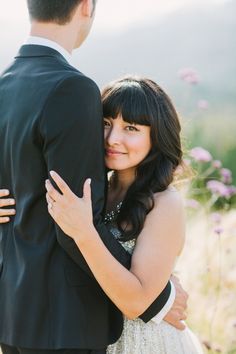 a young man and woman embracing each other in front of some wildflowers at their wedding