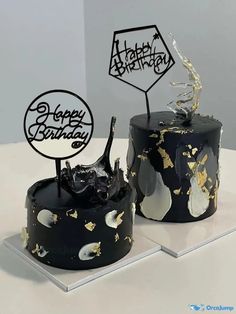 two black and white birthday cakes on display