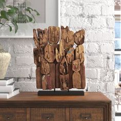 a wooden sculpture sitting on top of a dresser next to a potted plant and books