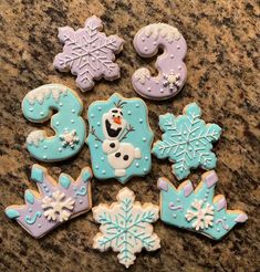 decorated cookies are arranged in the shape of numbers and snowflakes on a table