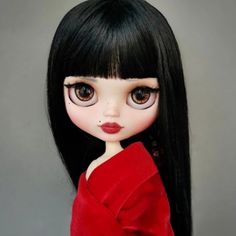 a doll with long black hair wearing a red dress