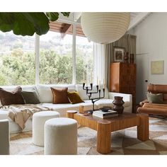 a living room filled with lots of furniture and large windows overlooking the trees in the distance