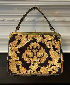 "C. 1950's. This stunning brocade tapestry handbag is embroidered with a gorgeous golden hue on a paisley design with leather, velvet and has gold hardware. The interior is satin lined with an inner zippered compartment and in great shape. The outside has a few minor flaws. The leather on the bottom of one side has a small rip and the opening flap is loose. I don't believe those detract from the beauty of this at all though. I love it but please see all photos!  Measurements: 8 1/2\"x 10\" not including handle" Tapestry Handbag, Tapestry Handbags, Paisley Design, Clutch Handbag, Evening Bags, Gold Hardware, Purses And Handbags, Clutches, Paisley