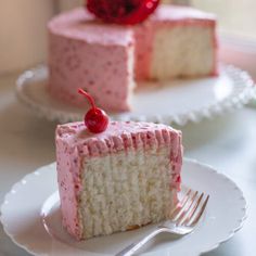 there is a piece of cake with pink frosting on it and a cherry on top