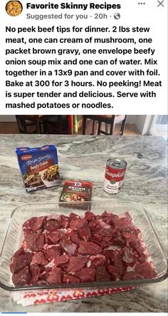 a glass dish filled with raw meat next to two cans of canned food on top of a table