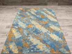 a blue and yellow area rug with wood flooring in the background on top of a hard wood floor