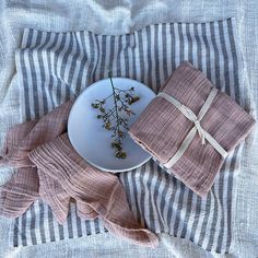 a white plate topped with a flower next to two napkins on top of a bed