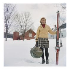 a woman standing in the snow with her skis