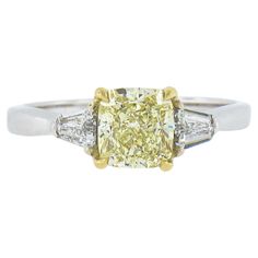 This gorgeous classic diamond engagement ring features a stunning, GIA certified, 1.44 carat light yellow diamond graded as a stunning modified brilliant cushion diamond with W to X color range and near flawless VVS2 clarity. This center stone is set in a solid yellow gold basket that slightly enhances and enriches its color. It is flanked on either side with two fine quality, custom tapered cut, white diamonds that perfectly complement the center stone and add a glamorous look to this elegant 3 Gia Certified Yellow Wedding Ring, Luxury Brilliant Cut Yellow Rings, Yellow Gia Certified Diamond Wedding Ring, Gia Certified Yellow Diamond Round Ring, Light Yellow Diamond, Brilliant Cut Diamond Engagement Ring, Canary Yellow Diamond Ring 1stdibs, Classic Diamond Engagement Ring, Gold Basket